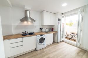 a kitchen with white cabinets and a washer and dryer at ALFALFA B Apartments in Madrid
