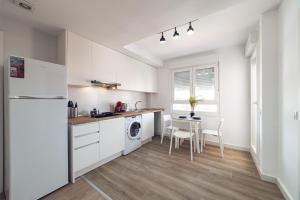 una cocina con armarios blancos y una mesa con sillas. en ALFALFA ATICO Apartments, en Madrid