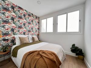 1 dormitorio con 1 cama grande y papel pintado con motivos florales en Crysoyle Apartment Barcelona Next to Camp Nou, en Hospitalet de Llobregat