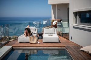 a woman laying on a couch next to a swimming pool at Alectrona Living Crete, Olīvea Luxury Apartment in Plataniás