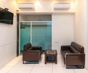 ムンバイにあるTreebo Trend Laaiba Residencyの革張りの椅子2脚とテーブルが備わる待合室