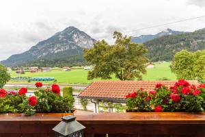 a view of mountains from a balcony with red flowers at Ferienwohnung Reschberg in Farchant