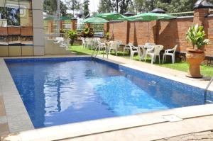 una piscina blu con sedie e ombrelloni di Hotel Karisimbi a Kigali