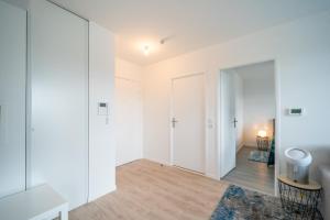 an apartment with white walls and a hallway with a mirror at Carré d'As - Appartement de standing in Le Bourget