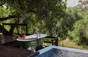a woman sitting in a bath tub next to a pool at Royal Malewane in Thornybush Game Reserve