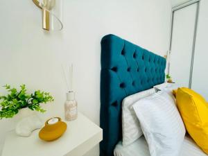 a bed with a blue headboard and a yellow bottle on a table at Apartament Vipii’s Residence in Arad