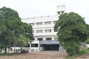 a white building with trees in front of it at HOTEL PRITAM PARK in Jālgaon