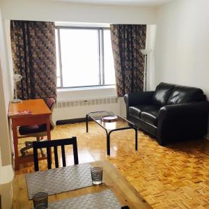 ein Wohnzimmer mit einem schwarzen Ledersofa und einem Tisch in der Unterkunft Stylish Montreal Apartment: Comfortable Stay in the Golden Square Mile in Montreal