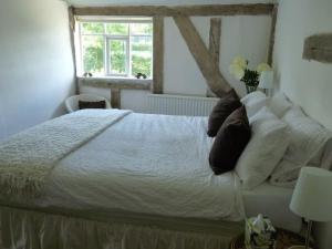 a bedroom with a white bed with pillows and a window at White Sheep Cottage in Peasenhall