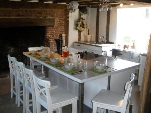 a kitchen with a large white island with white chairs at White Sheep Cottage in Peasenhall