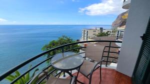 a balcony with a table and chairs and the ocean at The Best Atlantic Ocean View in Câmara de Lobos