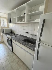La cuisine blanche est équipée d'un évier et d'un réfrigérateur. dans l'établissement Cómodo departamento céntrico, à Mendoza
