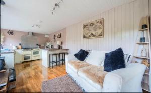 a living room with a white couch and a kitchen at Clematis cabin in Hereford