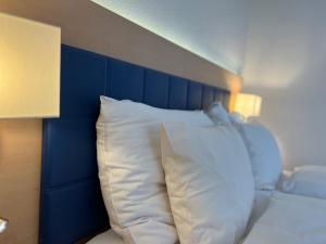 a bed with a blue headboard and white pillows at Vinum at Felmis SELF CHECK-IN in Lucerne