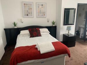 a bedroom with a bed with a red and white blanket at Trinity Guest House in Hartlepool