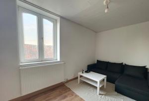 a living room with a blue couch and a window at Charbonnel 1 B Charleroi-airport in Charleroi