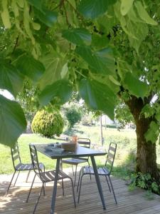 een tafel en stoelen op een terras onder een boom bij LA FERME JARLAN in Berganty