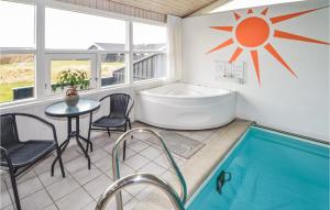 a bathroom with a tub and a table and chairs at Nice Home In Hjrring With 4 Bedrooms, Sauna And Indoor Swimming Pool in Lønstrup