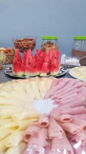 a table topped with cheese and meats and fruit at Hostel Caminho da Praia in Arraial do Cabo