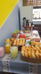 a table topped with baskets of bread and other food at Hostel Caminho da Praia in Arraial do Cabo