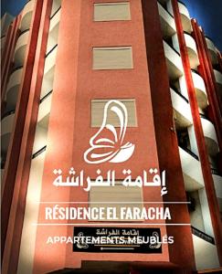 Un alto edificio rosso con un cartello sopra di Residence ElFaracha a Sousse