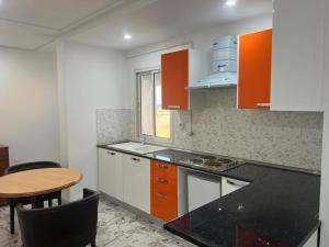 une cuisine avec des placards orange et blancs et une table dans l'établissement Residence ElFaracha, à Sousse