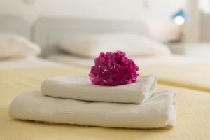 una flor púrpura sentada encima de las toallas en una cama en Edgewater Studios, en Kissamos