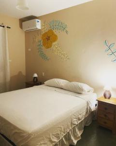 1 dormitorio con 1 cama con una flor en la pared en Pousada As Ondas, en Guarujá