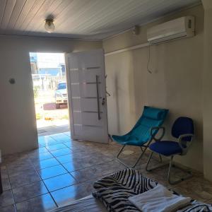 a room with a door and two chairs and a bed at Kitnet casal e apartamento com lareira e vista jardim in Esteio
