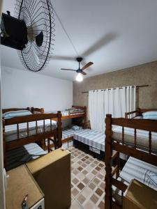 a room with four bunk beds and a fan at Hostel Caminho da Praia in Arraial do Cabo