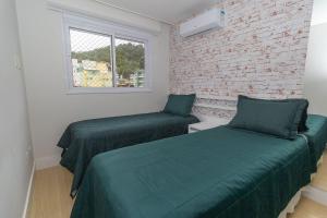 a bedroom with two beds and a brick wall at Boulevard 221D - Excelente apartamento em condomínio de luxo no centro de Bombinhas - Piscina - Jacuzzi - Academia - Portaria 24h - (Consultar serviços de roupa de cama e banho) in Bombinhas +35 photos