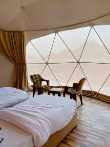a bedroom with a bed and two chairs in a tent at Yellow Star Camp Wadi Rum in Wadi Rum