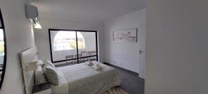 Un dormitorio con una cama y una ventana grande. en ENJOY POOL, BEACH and more at this nice apartment only 3 minutes from Mareta's Beach, en Sagres