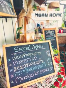 a chalkboard sign on a table with a menu at ม่วนโฮม muan home café&stay in Ban Don