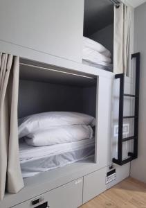 a white bunk bed with white pillows in it at Aloha Surf Hostel in Somo