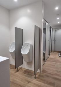 a bathroom with three urinals and a row of mirrors at Aloha Surf Hostel in Somo