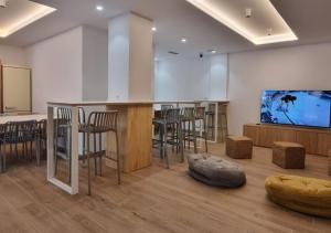 a room with a bar with chairs and a flat screen tv at Aloha Surf Hostel in Somo