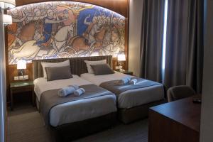 two beds in a hotel room with a mural on the wall at Orienta Hotel Gyumri in Gyumri