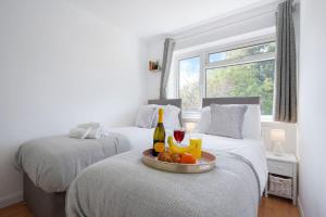 two beds with a tray of fruit and a bottle of wine at 5 Bedroom Detached House - Close to City Centre - Sleeps up to 10 guests with Free Parking, Fast Wifi, SmartTVs and Large Garden by Yoko Property in Milton Keynes