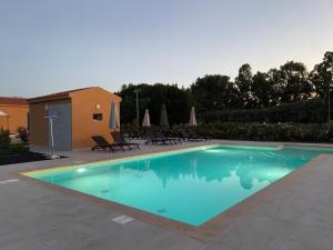 una piscina in un cortile con sedie e ombrelloni di Maris Suite - Appartamento con vasca idromassaggio ad Alghero