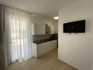 a kitchen with white cabinets and a sink and a window at Maris Suite - Appartamento con vasca idromassaggio in Alghero