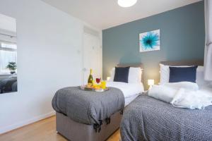 a bedroom with two beds and a table with drinks on it at 5 Bedroom Detached House - Close to City Centre - Sleeps up to 10 guests with Free Parking, Fast Wifi, SmartTVs and Large Garden by Yoko Property in Milton Keynes