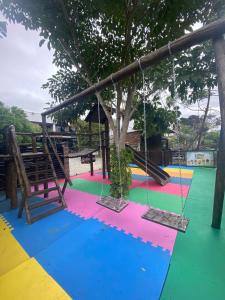 a colorful playground with a swing and a tree at Pousada Bella Casa in Balneário Camboriú