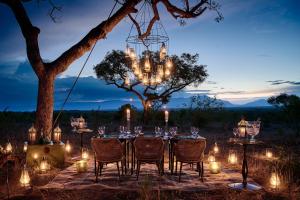 een lange tafel met stoelen en een kroonluchter bij Royal Malewane in wildreservaat Thornybush