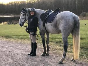 Uma mulher está ao lado de um cavalo. em Skedala horsefarm em Halmstad