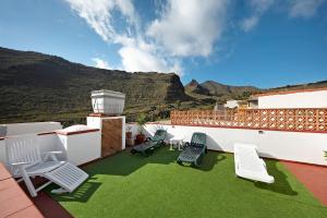 a patio with lawn chairs and mountains in the background at Ático El Agua in Santiago del Teide