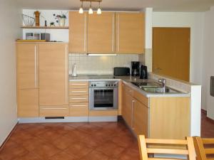 a kitchen with wooden cabinets and a sink and a stove at Holiday Home Müritz Ferienpark Röbel-22 by Interhome in Röbel