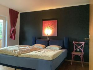 a bedroom with a blue bed and a pink chair at Charmantes Landhaus mit Garten und traumhaftem Fernblick in Thal