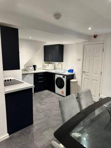 uma cozinha com electrodomésticos a preto e branco e uma mesa e cadeiras em Modern 2 Bedroom Apt Derby City em Derby