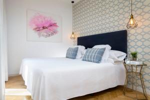 a white bed with two pillows on it in a bedroom at Puerta Catedral Indias Lofts in Seville